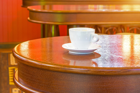 White cup of coffee on a wooden table in a cafeの写真素材