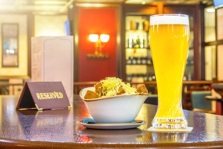 A glass of unfiltered beer with rusks cheese, a tablet - is reserved on a wooden table in the restaurant barの写真素材