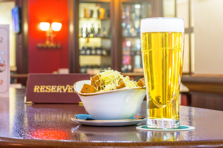 A glass of light beer with rusks cheese, a tablet - is reserved on a wooden table in the restaurant barの写真素材
