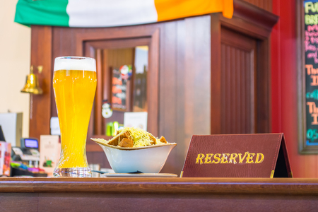 A glass of unfiltered beer with rusks cheese, a tablet - is reserved on a wooden table in the restaurant barの写真素材
