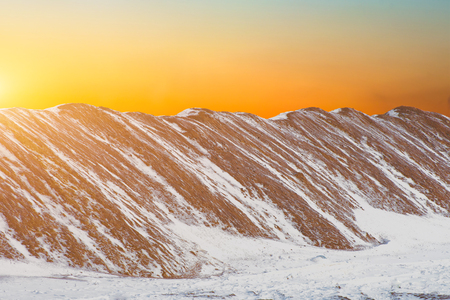 Sand dunes covered with white snow, ice, frost at sunsetの写真素材