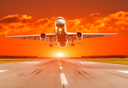 Passenger airplane landing at sunset on a runwayの写真素材