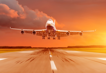 Passenger airplane landing at sunset on a runwayの写真素材