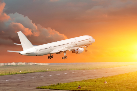 Passenger airplane landing at sunset on a runwayの写真素材