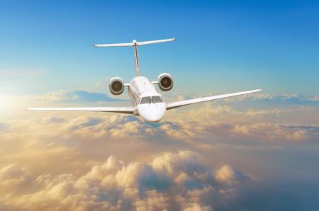 Flying airplane above the clouds horizon sky with bright sunset colorsの写真素材