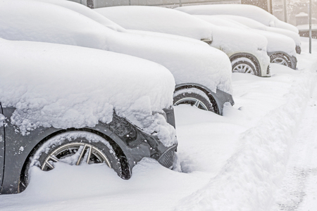 Snow covered ows of cars in the parking lot. Urban scene, snowstorm. Clean automobile from the snowの写真素材