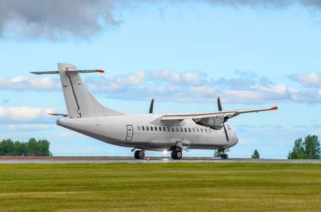Passenger turboprop airplane landing the runway against the blue skyの写真素材