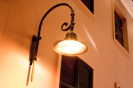 An old street lamp on a house with windowsの写真素材