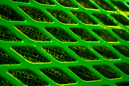 Green metal lattice lozenge rhombus close-up, under a fine metal gridの写真素材