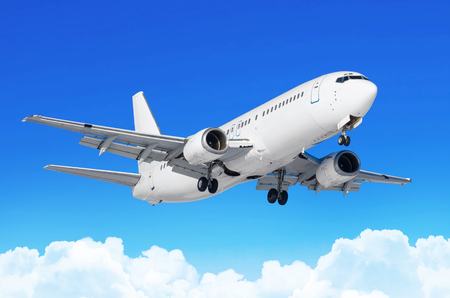 Passenger airplane with the chassis released before the landing at the airport against the blue sky cumulus cloudsの写真素材