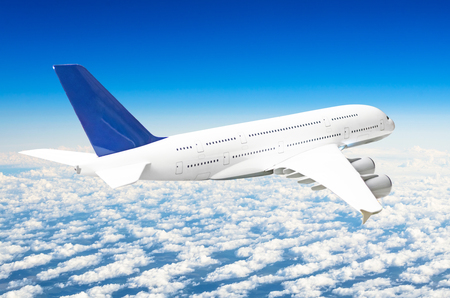 Passenger huge liner airplane fly above clouds and blue skyの写真素材