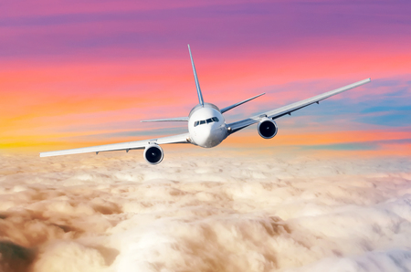 Passenger airplane flying airplane above the clouds horizon sky with bright sunset colors., the view is exactly on the cockpit of the pilotsの写真素材