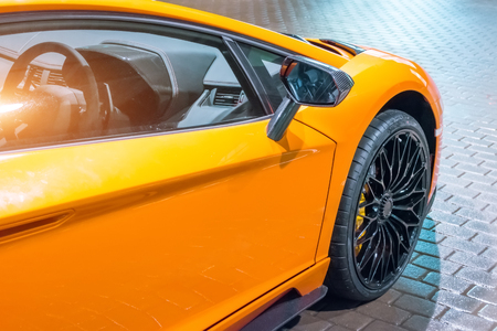 Front wing and the wheel of the car are a supercar, at night in a parking lot in the cityの写真素材