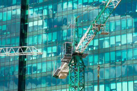Construction crane on building skyscraper apartment house, on a background of glass texture of financial offices windowsの写真素材