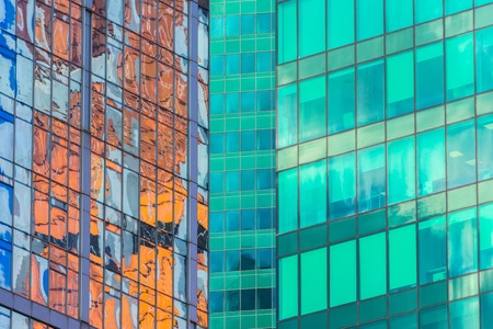 Angle glass red, burgundy, brown, green, aqua clolrs facades of a window of financial skyscrapers, a corner of a building close-upの写真素材