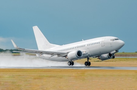 An airplane lit by the sun takes off in a wet runway during the rain at the airportの写真素材