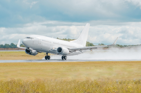 Airplane lit by the sun takes off in a wet runway during the rain at the airportの写真素材