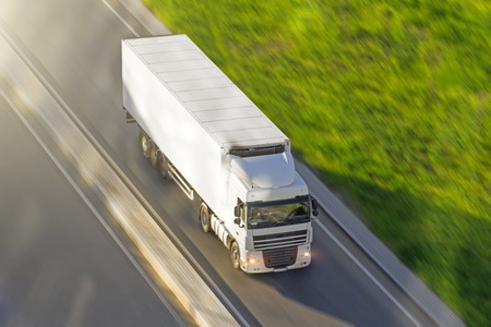 Large truck with a trailer on the highway at a speed that moves along the asphalt, view from aboveの写真素材