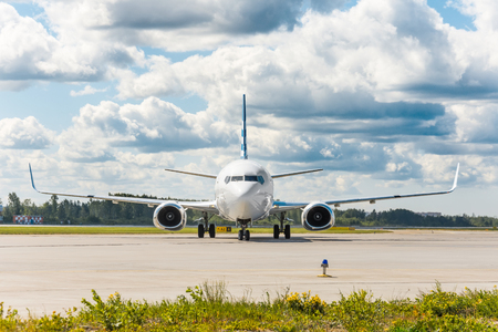 Aircraft on the steering track at the airport, exactly in the middle in the frame, against the backdrop of a picturesque sky in the cloudsの写真素材