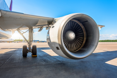 View of the wing and the big engine of the aircraft in the parking lot at the airport, the platform on a sunny dayの写真素材