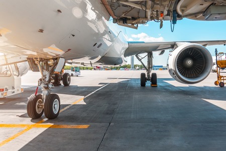 View of front chassis, wing and the big engine of the aircraft in the parking lot at the airport, the platform on a sunny dayの写真素材