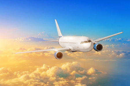 Passenger airplane flies in the sky against the background clouds during sunsetの写真素材