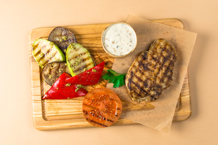 BBQ Steak, meat, vegetables squash eggplants and tomatoes, pepper roasted on a wooden board. Top view on a brown backgroundの写真素材