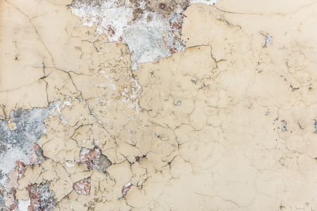 Old white paint exfoliates with cracked layers on the wall of concreteの写真素材