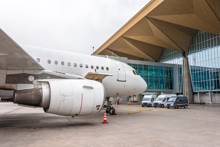 Commercial passenger airplane in the parking at the airport terminal with a nose forward and a gangway - front view. Service and preparation for the flightの写真素材