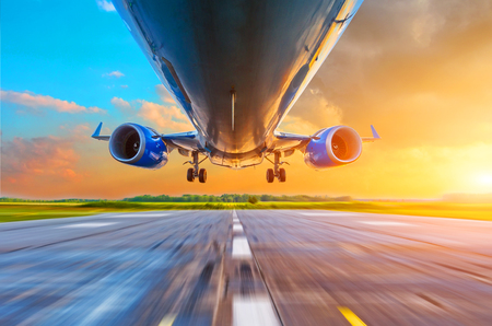 Passenger airplane landing at sunset on a runway. View of engines, fuselage, chassisの素材 [FY310103853818]