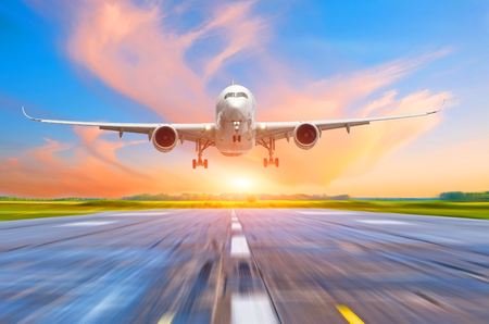 Passenger airplane landing at sunset on a runwayの写真素材