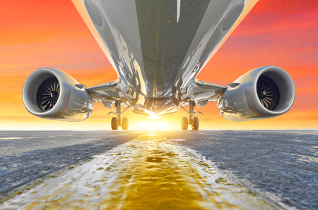 Airplane in the parking lot of the airport apron, bottom view hdr of engines, fuselage and wings. Against the background of the sky sunset red pink sky cloudsの写真素材