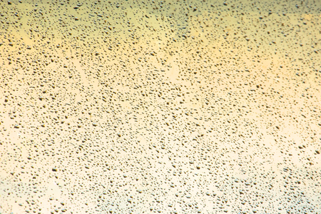 Rain drops on window glasses surface with warm shade backgroundの写真素材