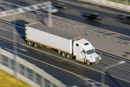 Large truck with a trailer on the highway at a speed that moves along the asphalt, evening sunset light. View from aboveの写真素材