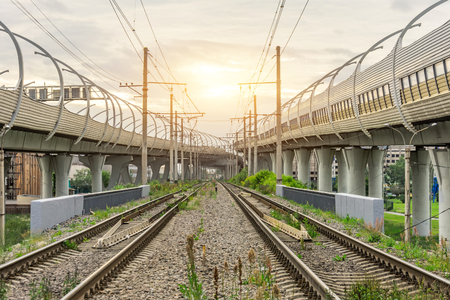 View of railway tracks and highway bridges at sunsetの写真素材