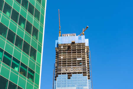 Construction crane on building skyscraper apartment house, on a background of glass texture of financial offices windowsの写真素材