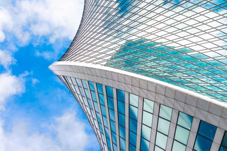 Reflection of sky and clouds in glass spiral, wave with bend facade windows of financial skyscrapersの写真素材