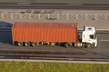 Large truck with container trailer on the highway asphalt, evening sunset light. View from aboveの写真素材