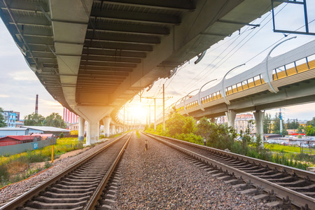 View of railway tracks and highway bridges at sunsetの写真素材