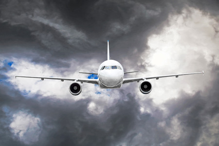 Passenger airplane flies through the turbulence zone through the lightning of storm clouds in bad weatherの写真素材