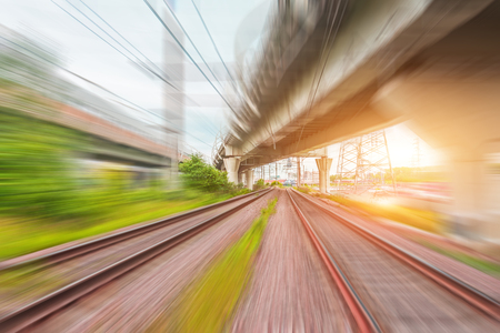 View of railway tracks motion blur and highway bridges at sunsetの写真素材