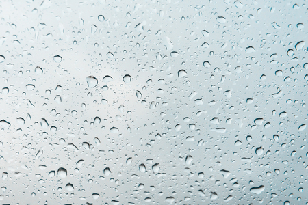 Drops of water on a glass against a gray cloudy skyの写真素材