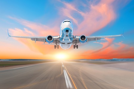 Airplane take off from runway airport in the evening at sunset, the sky and picturesque cloudsの写真素材