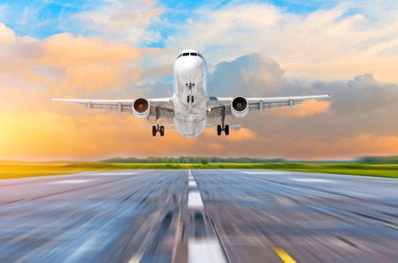 Airplane landing on runway airport in the evening at sunset, the sky and picturesque cloudsの写真素材