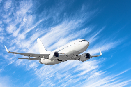 Flying passengers aircraft fly climb on a background of blue sky and cirrus cloudsの写真素材