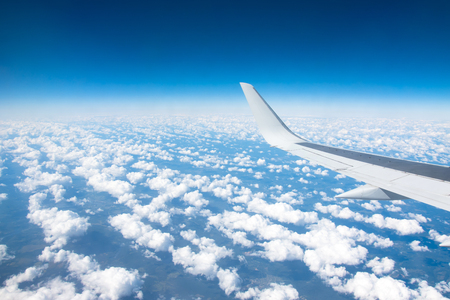 Wing view of the airplane on a winglets and jet engine, fluffy clouds on the skyline during climbing flight levelの写真素材