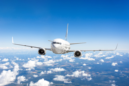 Airplane flies over the summer clouds and the earth's surface under the blue skyの写真素材