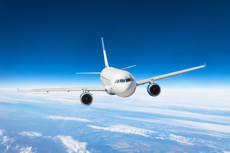 Airplane fly over the clouds and the earth's surface under the blue skyの写真素材