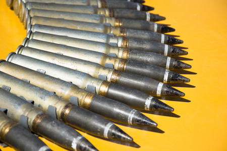 Number of cartridges from machine gun folded in a semicircle on a yellow backgroundの写真素材