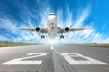 Airport runway number 28 and airplane take off to in horizon and picturesque cirrus clouds in the blue skyの写真素材